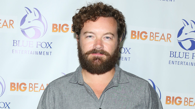 Danny Masterson posing for photographers while wearing a grey collared shirt