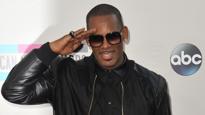 R. Kelly smiling and saluting a group of photographers