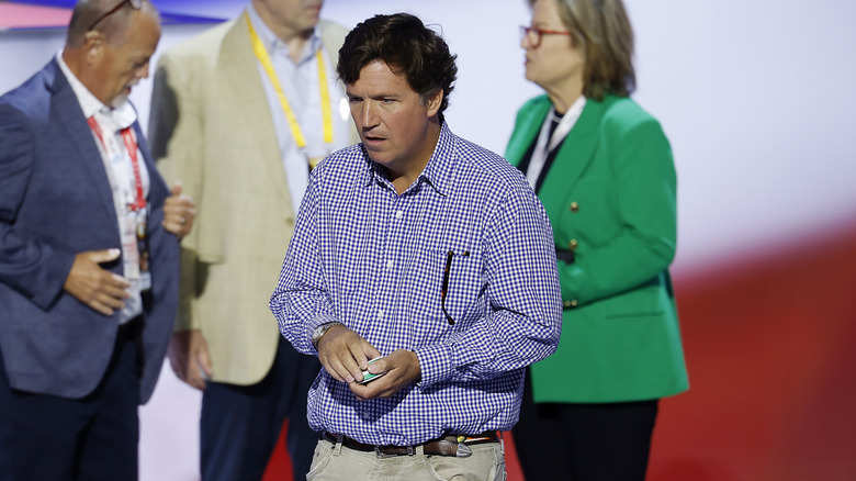 Candid photo of Tucker Carlson at the 2024 RNC wearing a poorly fitted button-up shirt