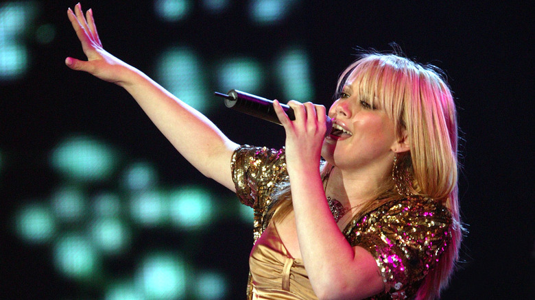 Hilary Duff performing, wearing glittery gold bolero