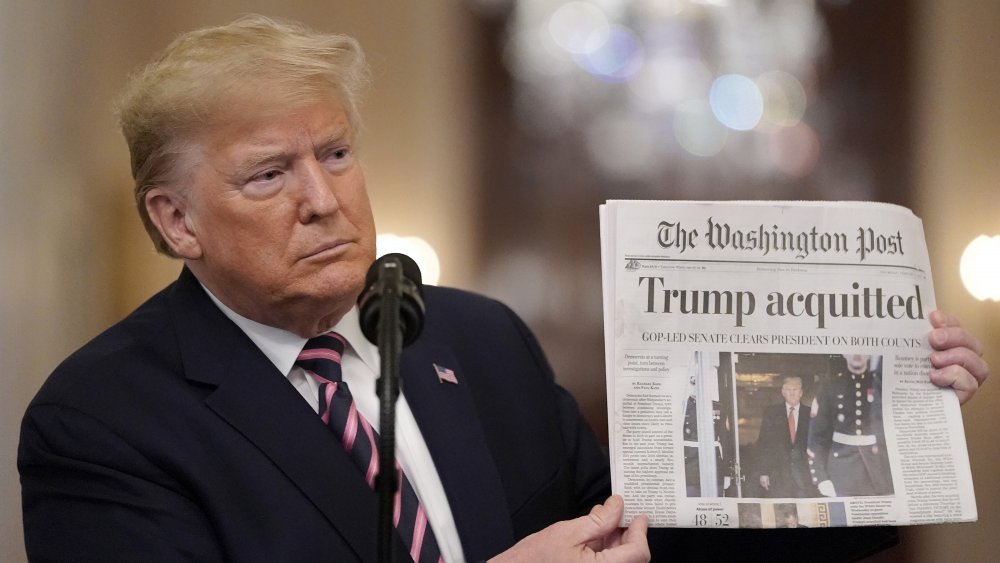 Donald Trump holds up newspaper in February 2020 after being acquitted