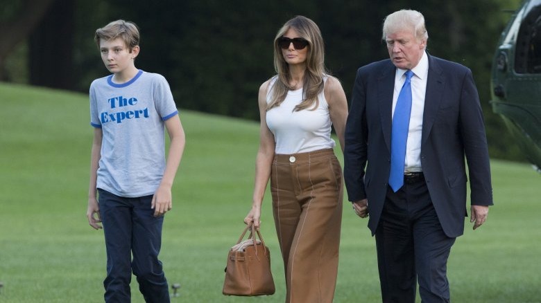 Barron Trump, Melania Trump, and Donald Trump walking outside