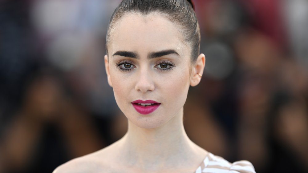 Lily Collins staring blankly at a red carpet event 
