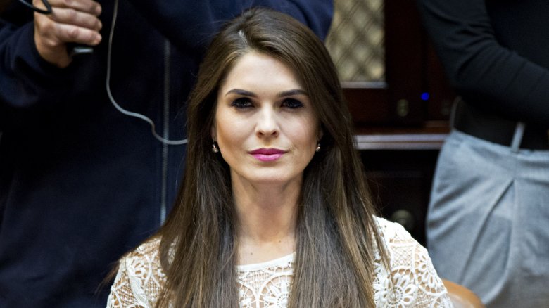 Hope Hicks in a white top, sitting in a meeting with a serious expression