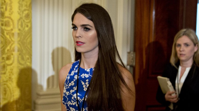 Hope Hicks in a blue floral dress, walking with a serious expression