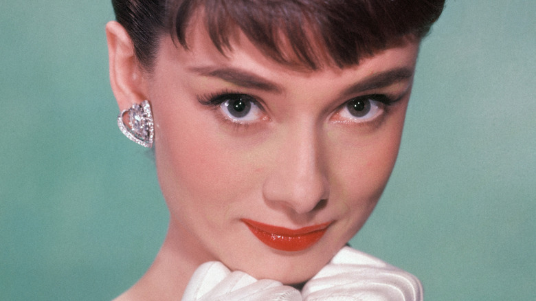 Aubrey Hepburn smiling, gloved fists tucked under chin