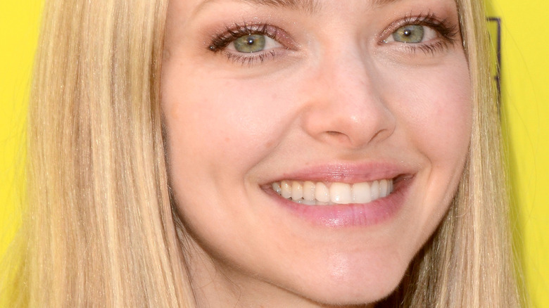 Amanda Seyfried smiles in front of a yellow background