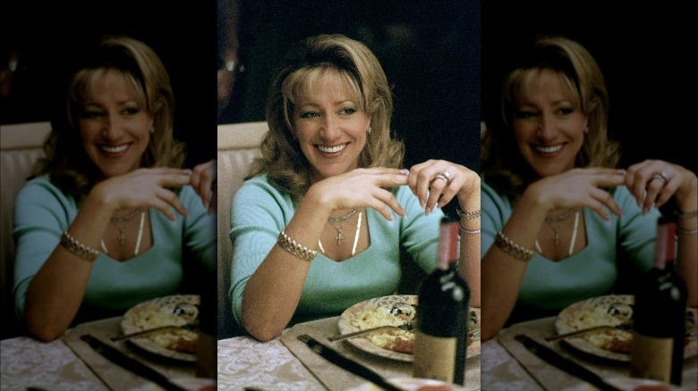 Edie Falco as Carmela Soprano in front of wine bottle.