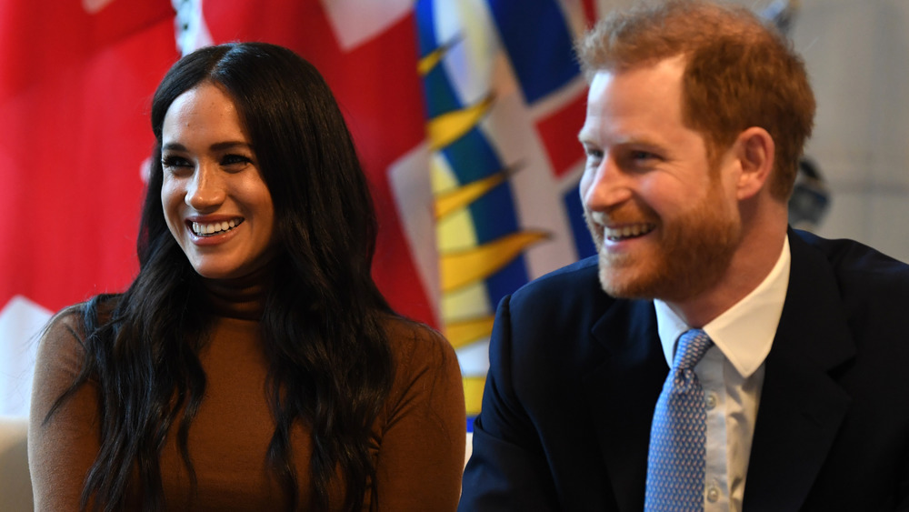 Meghan Markle and Prince Harry smiling while sitting down