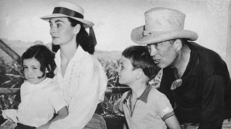 Anjelica Huston in her mother's lap next to John Huston and her brother in 1957