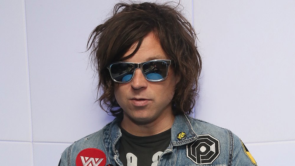 Ryan Adams in a light blue denim jacket and sunglasses, with a neutral expression