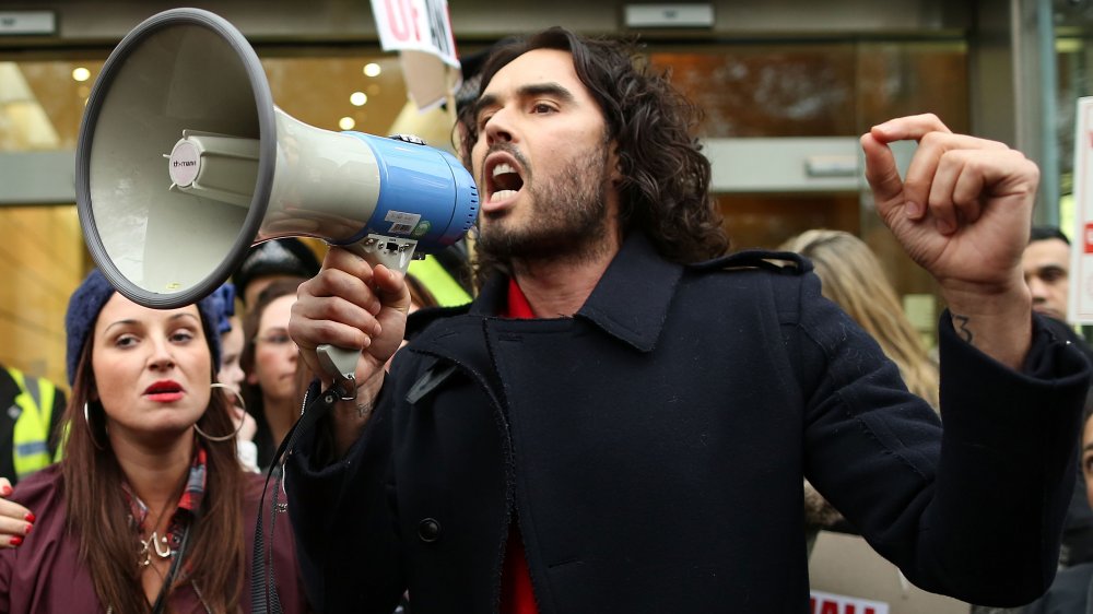 Russell Brand speaking into a megaphone at a protest in London 