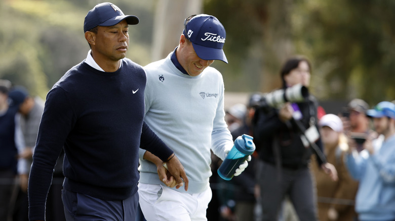 Tiger Woods handing Justin Thomas the tampon