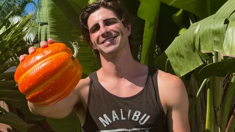 Caleb Graves smiling while holding a small pumpkin