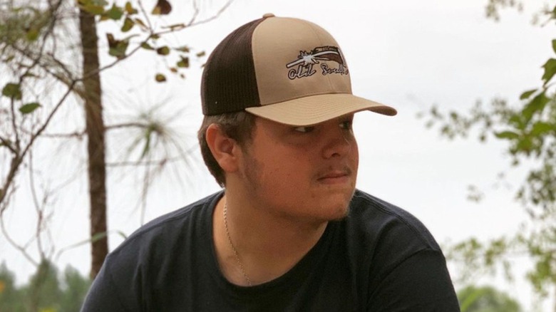 Timothy Hall wearing a black shirt and hat by the water