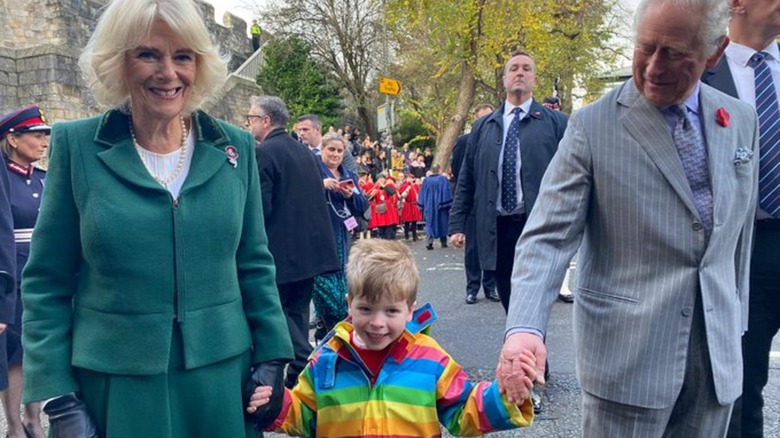 Camilla and Charles holding boy's hand 