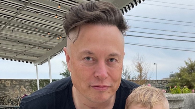 Elon Musk with a Viking haircut posing with his son