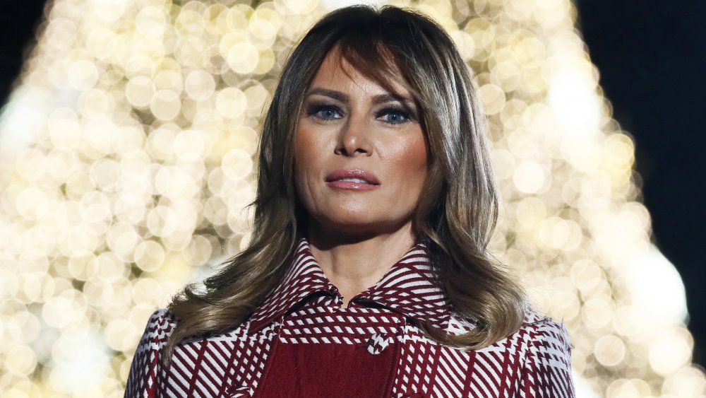 Melania Trump in front of bright white Christmas tree
