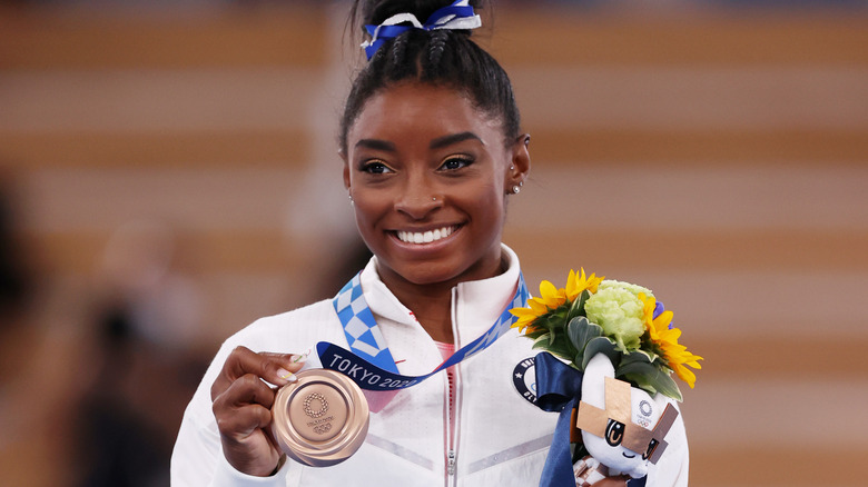 Simone Biles holds her bronze medal