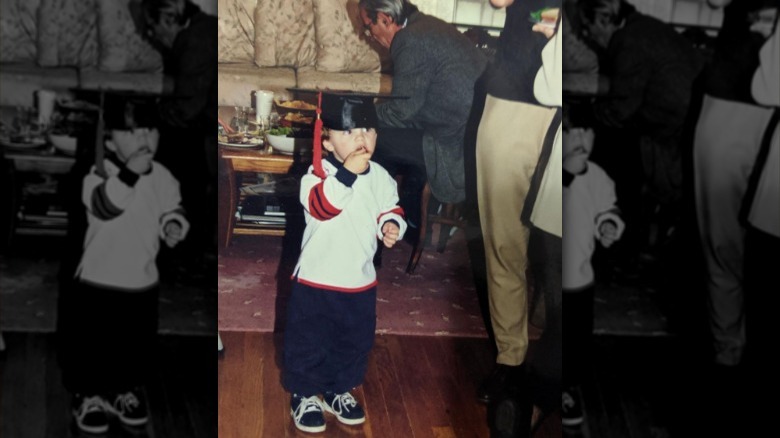 Timothée Chalamet as a young boy wearing a graduation cap