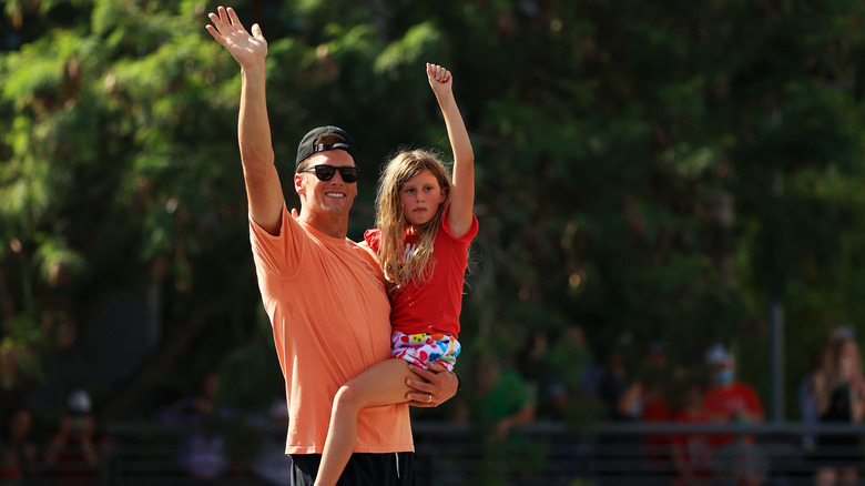 Tom Brady and daughter waving on a parade boat