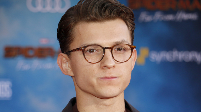 Tom Holland wearing glasses with serious expression