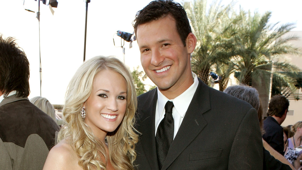 Tony Romo and Carrie Underwood posing on red carpet