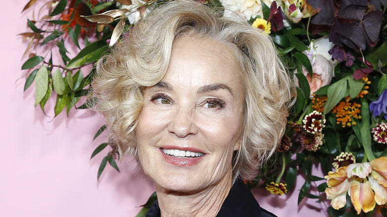 Jessica Lange smiling in front of flower backdrop