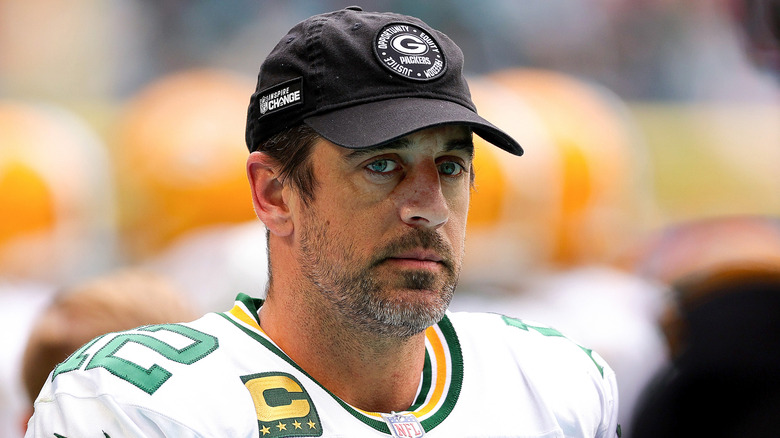 Aaron Rodgers wearing a white Green Bay Packers uniform and a black hat