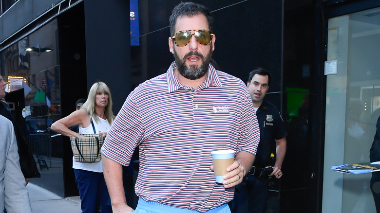 Adam Sandler holding coffee on sidewalk