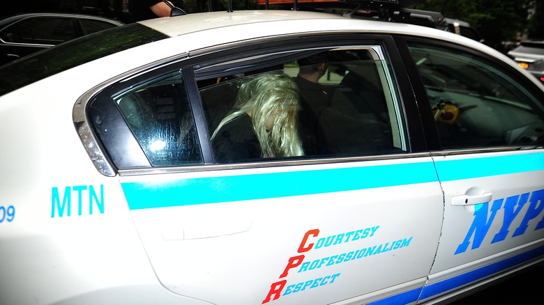 Amanda Bynes in backseat of police car, wearing blonde wig