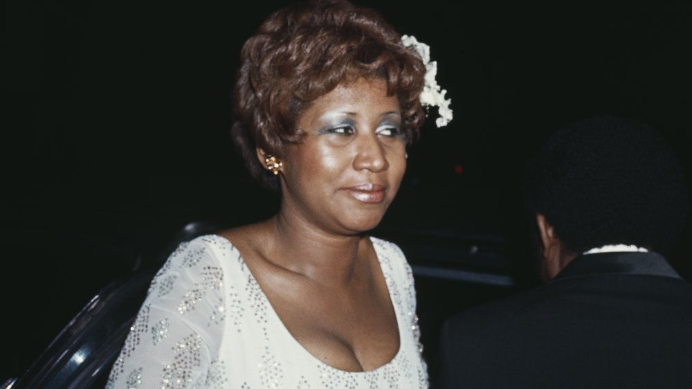 Aretha Franklin looking off to the side in a white dress