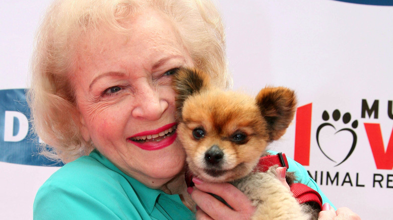 Betty White cuddling a dog 