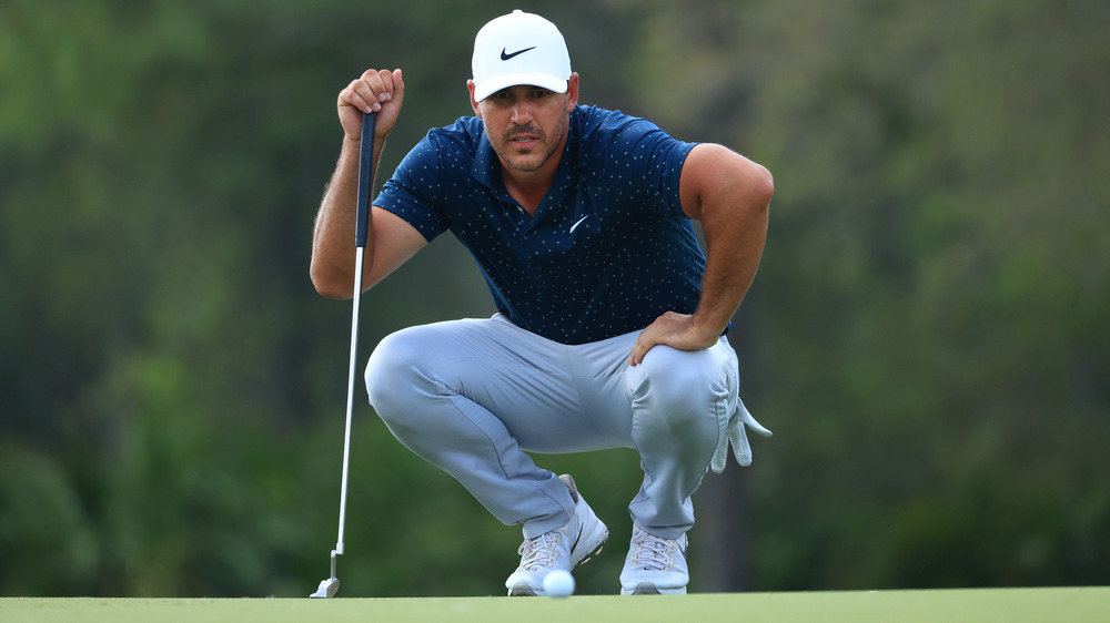 Brooks Koepka squatting down on golf course