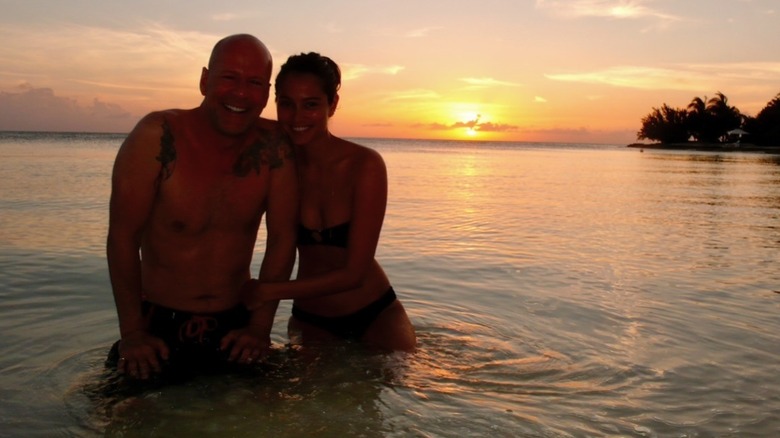 Old picture of Bruce and Emma Heming Willis in water at sunset