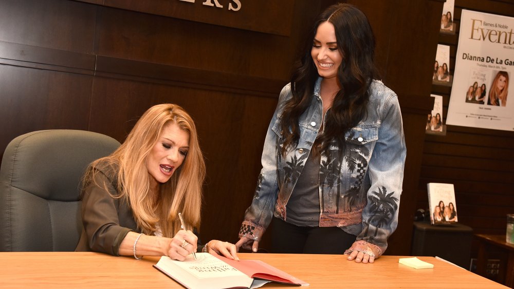 Dianna De La Garza signing a book, Demi Lovato standing next to her