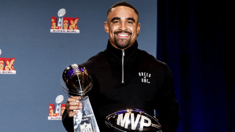 Jalen Hurts posing with The Vince Lombardi Trophy and the Pete Rozelle Trophy