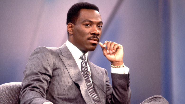 Eddie Murphy wearing a grey pinstripe suit and a white and grey checkered tie