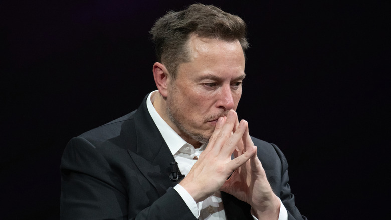 Elon Musk touching his hands; appearing to be deep in thought