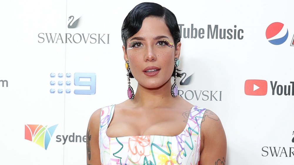 Halsey with short black hair, colorful eye makeup, and long earrings