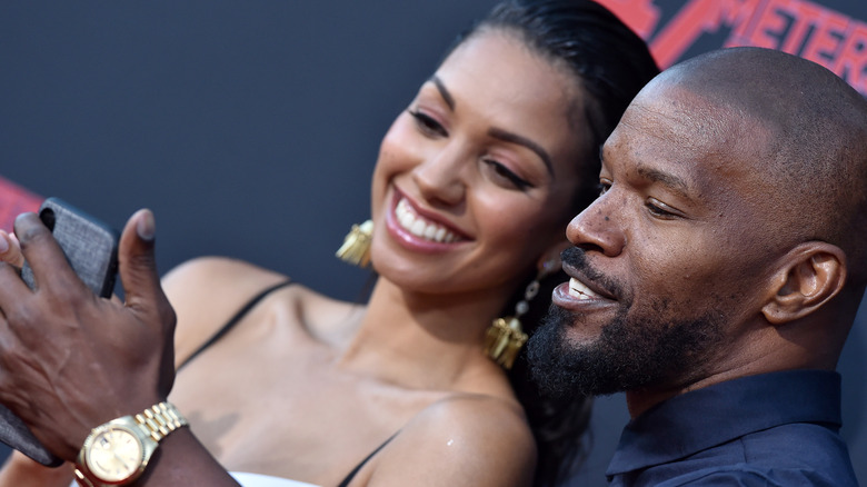 Corinne Foxx and Jamie Foxx looking at phone