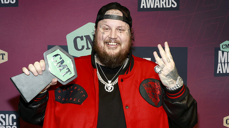 Jelly Roll smiling and holding up an award