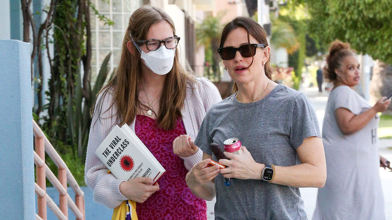 Violet Affleck walks with her Jennifer Garner while masked and holding The Viral Underclass