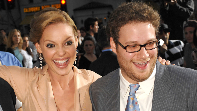 Katherine Heigl wearing a cream collared dress and Seth Rogen wearing.a grey suit and blue patterned tie