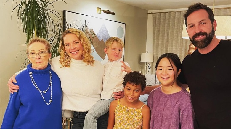 Katherine Heigl posing with her family while wearing.a white sweater