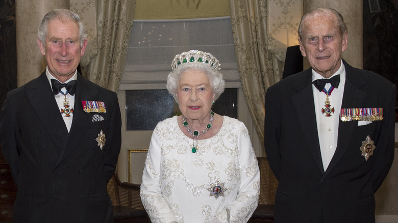 King Charles smiling, Queen wearing crown, Prince Philip grimace