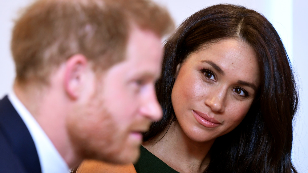 Meghan Markle looking at Harry, who is out of focus