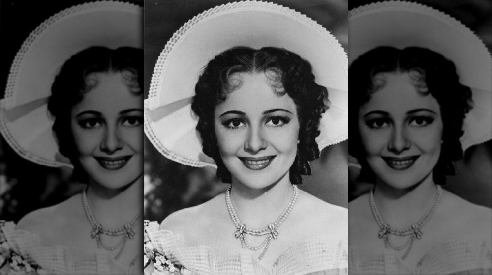 Black-and-white photo of Olivia de Havilland smiling, wearing a large hat