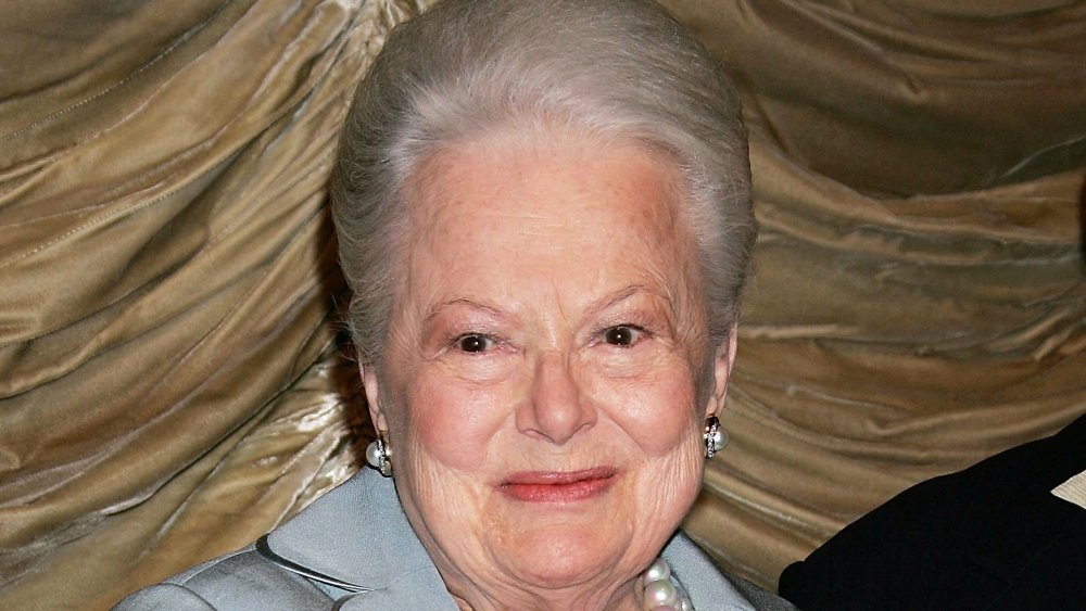 Olivia de Havilland in a blue outfit and pearls, smiling in 2006