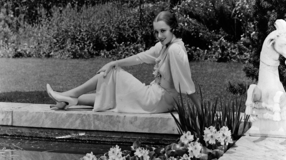 Black-and-white photo of Olivia de Havilland sitting in her garden in 1938